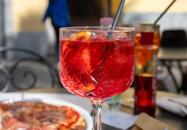 Orzeźwiający Aperol Spritz z plastrem pomarańczy, idealny na aperitivo. Pytasz gdzie zjeść w Mediolanie? To może być początek Twojej kulinarnej podróży!