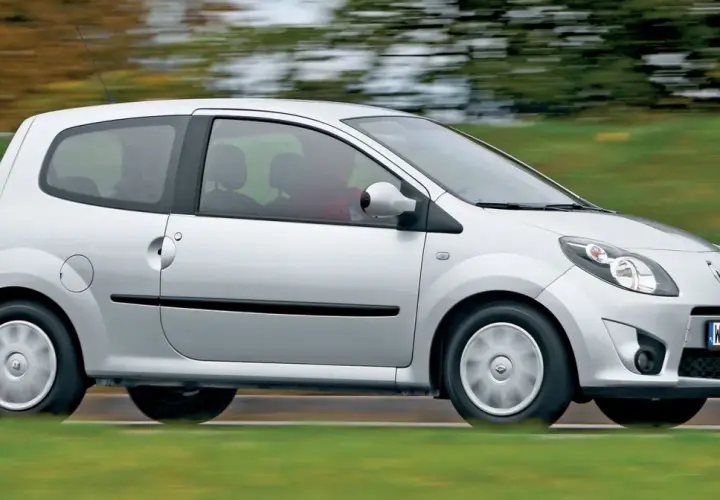 Srebrne Renault Twingo 2 w ruchu, z rozmazanym tłem zieleni i drzew.