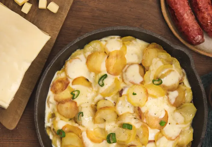 Plat gratiné de pommes de terre et fromage fondant, parfait pour une recette diots de Savoie. Accompagné de saucisses savoureuses.