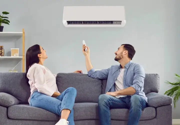 Pareja disfrutando del confort de su hogar con un aire acondicionado que ofrece un boost de aire fresco.