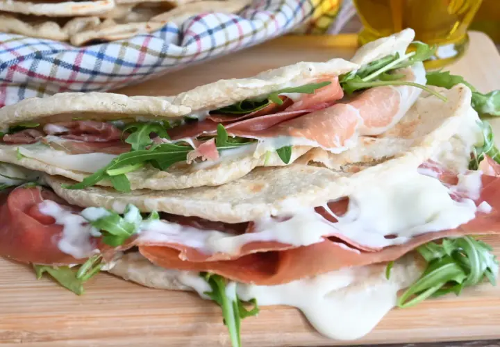 Piadina farcita con prosciutto crudo, mozzarella filante e rucola. Una ricetta piadina veloce e gustosa, perfetta per un pranzo o una cena informale.