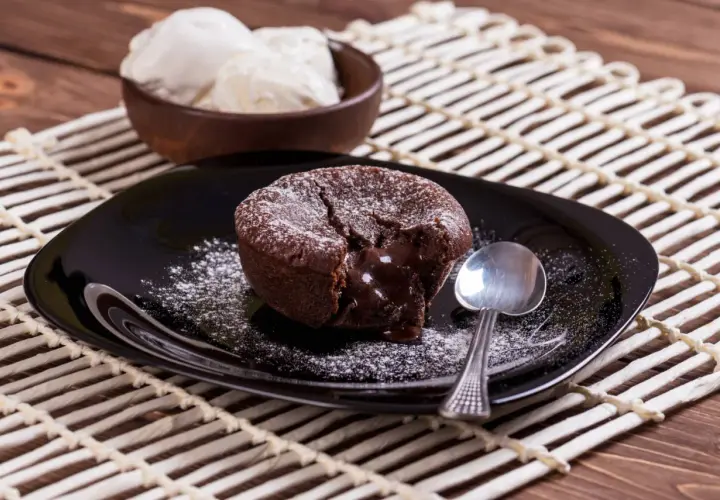 Un délicieux moelleux au chocolat, cœur coulant, saupoudré de sucre glace, servi avec de la glace à la vanille. Une recette gourmande à tester !