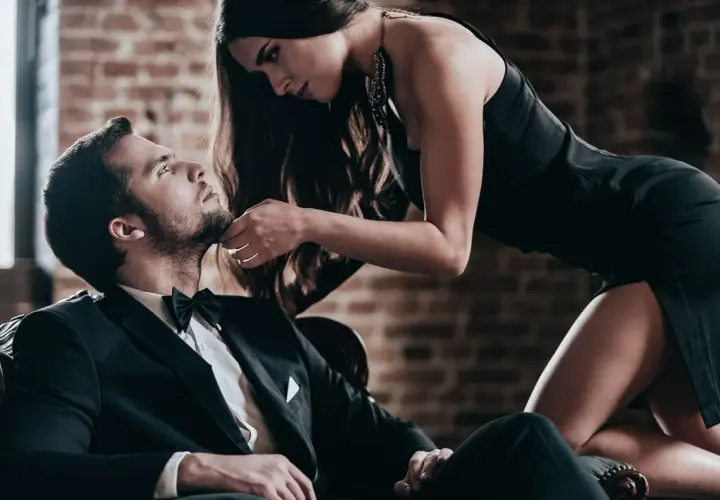 Elegancki mężczyzna w garniturze i kobieta w czarnej sukience. Sekret jak być atrakcyjnym tkwi w pewności siebie i spojrzeniu.