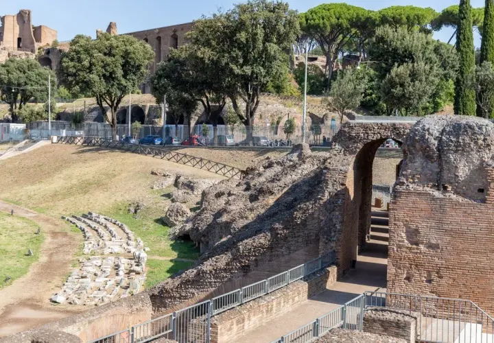 Ruines antiques du Circo Massimo à Rome, avec des gradins en pierre et une arche de briques menant à des escaliers.
