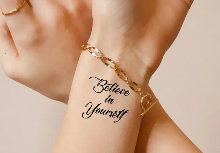 Dłoń z tatuażem "Believe in Yourself" i złotą bransoletką.