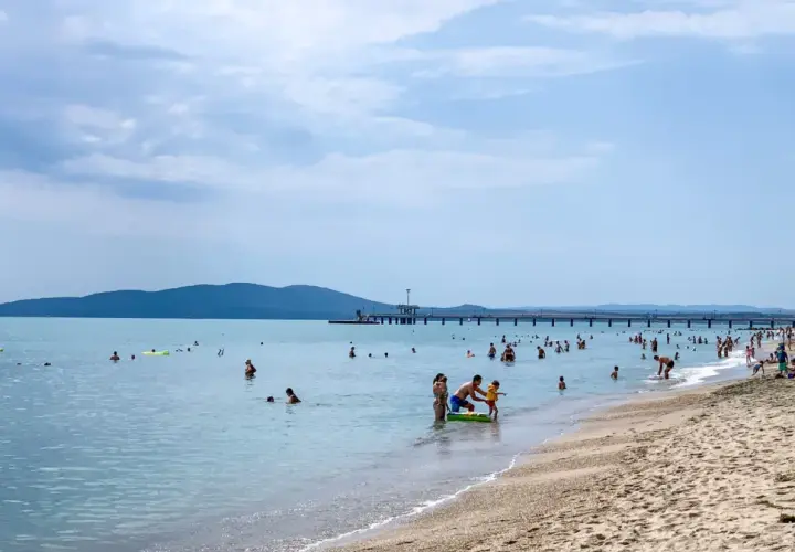 Plaża w Burgas, mnóstwo ludzi kąpiących się i opalających. Długie molo, góry w tle. Burgas czy warto? Zdecydowanie tak!