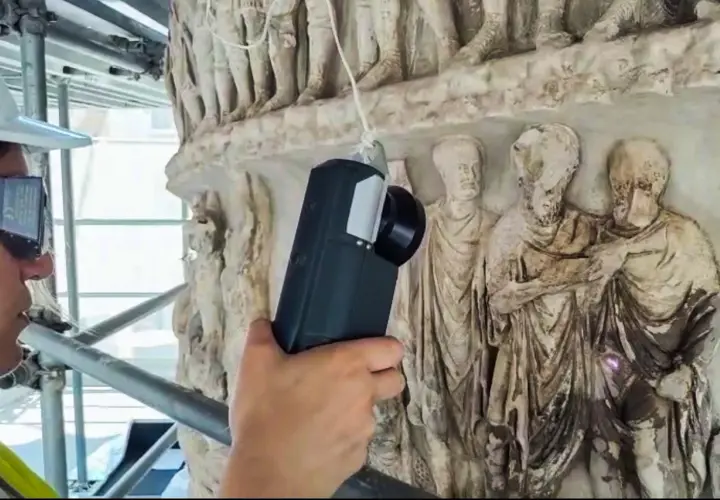 Tecnico con visore AR esamina i rilievi della Colonna di Marco Aurelio, creando un riassunto digitale della sua storia.