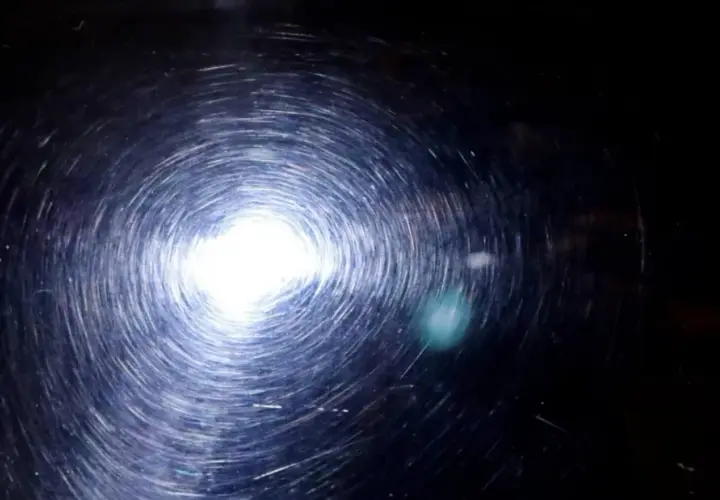 Efekt wiru po polerowaniu lakieru po malowaniu sprayem. Jasne światło odbija się od powierzchni, tworząc spiralne refleksy.