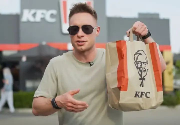 Mężczyzna trzyma torbę z KFC, zastanawiając się nad kalorycznością frytek.
