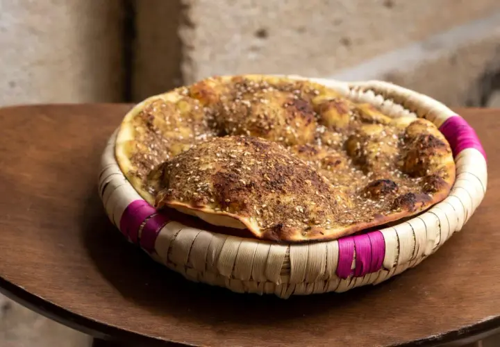 Manouche au zaatar, un délice croustillant aux épices, servi dans un panier tressé aux accents fuchsia.