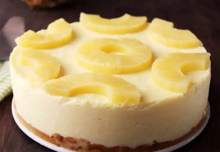 Tarta de piña cremosa, decorada con rodajas y trozos de piña fresca. Un postre tropical irresistible.