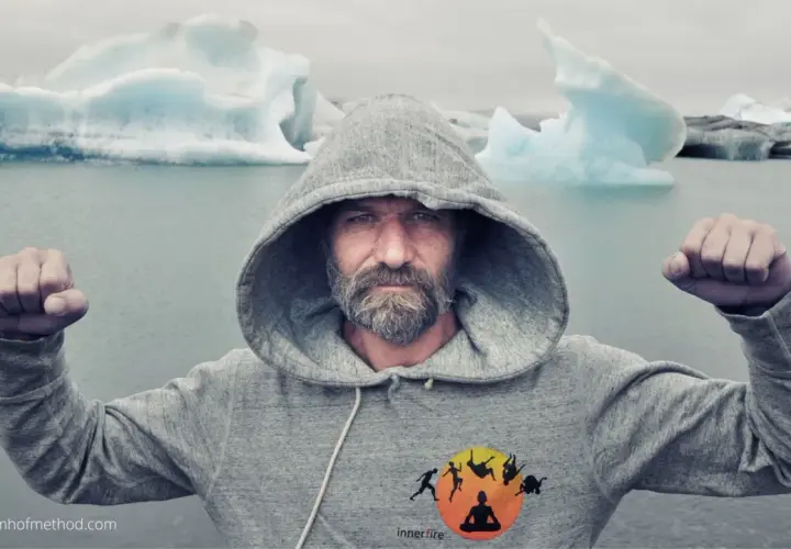 Wim Hof w szarej bluzie z kapturem, z zaciśniętymi pięściami, na tle lodowca. Siła i hart ducha.