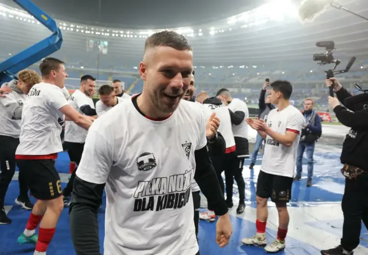 Piłkarze w białych koszulkach z napisem "Piłka nożna dla kibiców" świętują. To obraz z historii tabeli wszechczasów ekstraklasy.