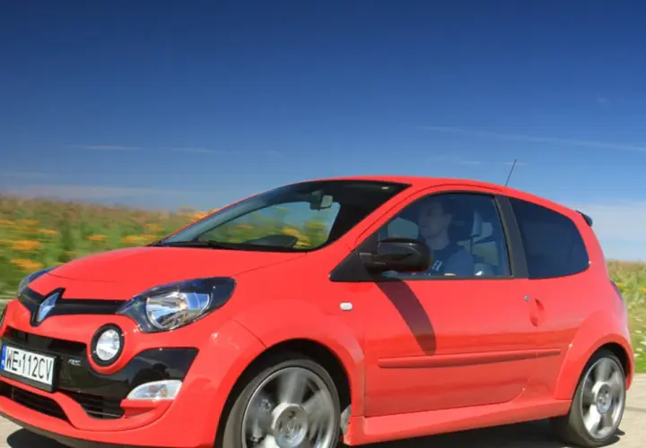 Czerwone Twingo RS pędzi przez kwitnące pola pod błękitnym niebem.