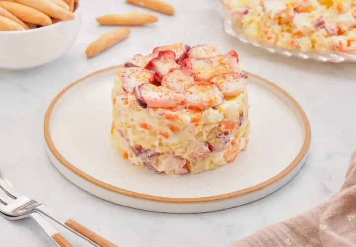 Deliciosa ensaladilla de pulpo, con patatas, zanahoria y huevo, coronada con trozos de pulpo y pimentón.