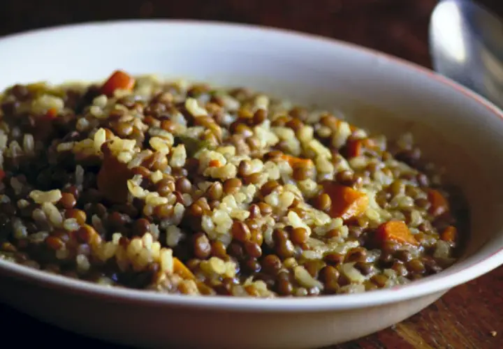 Un plato humeante de lentejas con arroz y trozos de zanahoria, listo para disfrutar.