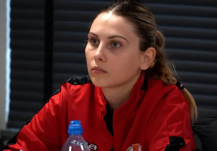 Młoda kobieta w czerwonej bluzie, przyszły trener UEFA A, słucha uważnie.