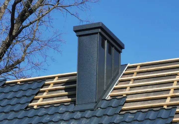 Nowy komin na dachu, widoczne łaty i kontrłaty pod dachówką.