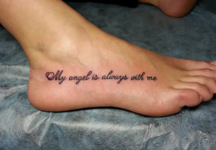 Najciekawsze tatuaż na stopie: napis "My angel is always with me" w eleganckiej czcionce.