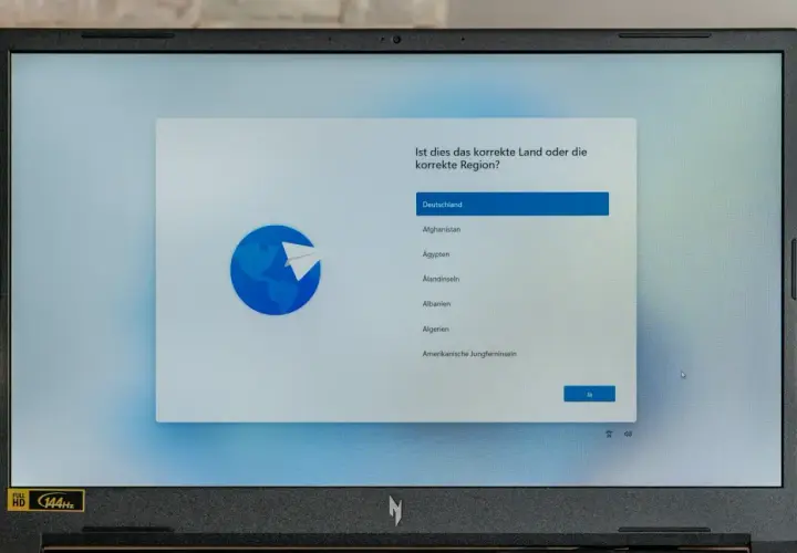 Ein Laptop zeigt die Windows 11 Einrichtung mit der Länderauswahl. Hier kann man Windows 11 ohne Microsoft Konto einrichten, indem man Deutschland wählt.