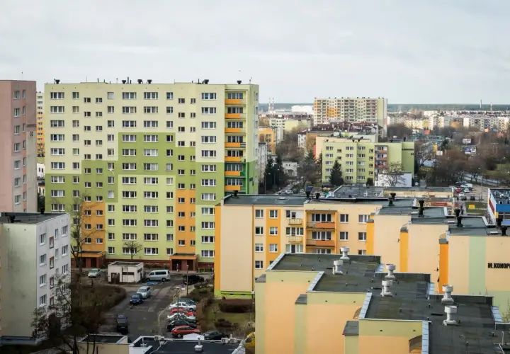 Widok na osiedle wielopiętrowych bloków mieszkalnych w pastelowych kolorach.