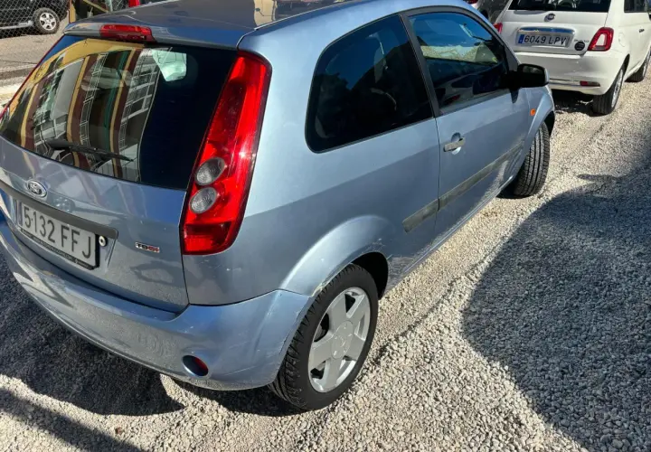 Ford Fiesta 1.4 TDCI con algunos problemas visibles, aparcado sobre grava.