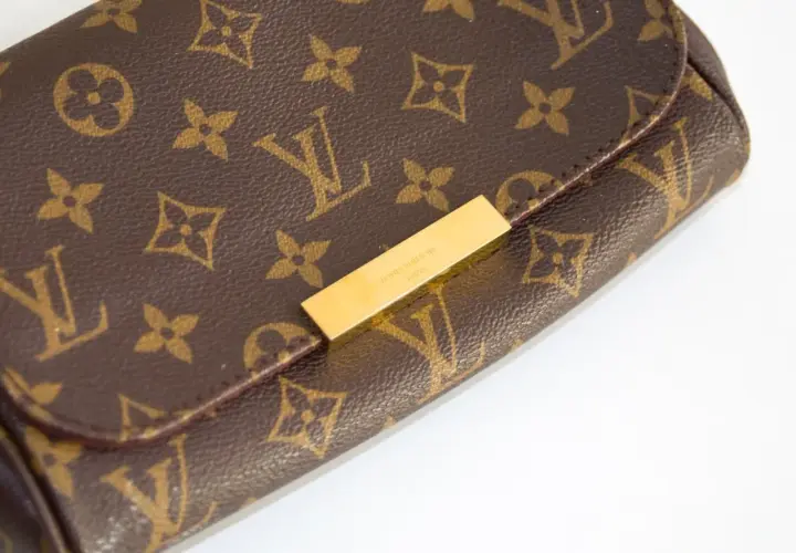 Złota blaszka z napisem "LOUIS VUITTON PARIS" na brązowej torebce z monogramem. Chcesz sprawdzić numer seryjny?