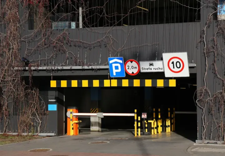 Znaki drogowe przy wjeździe na parking pod blokiem: zakaz wjazdu pojazdów o wysokości powyżej 2m, strefa ruchu, ograniczenie prędkości do 10 km/h.