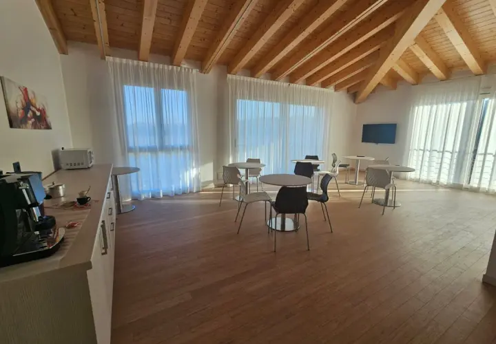 Pavimento per mansarda in legno chiaro, con travi a vista e arredi moderni.