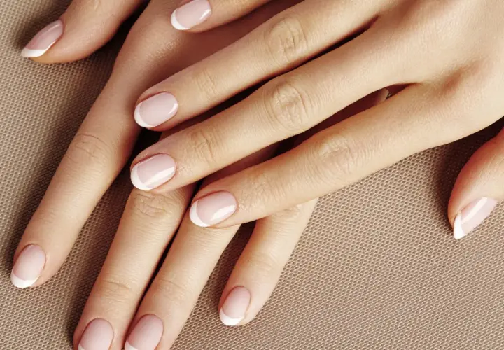 Dłonie z perfekcyjnym manicurem w stylu kok francuski. Delikatny róż i białe końcówki paznokci.