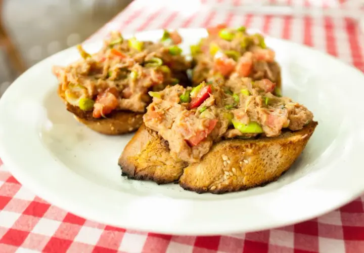 Trzy chrupiące kromki chleba z pastą z tuńczyka, pomidorów i zielonej cebulki. Idealna bruschetta z tuńczykiem na letni obiad.