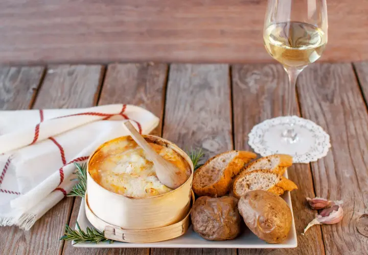 Un Mont d'Or au four, pommes de terre, pain et vin blanc. Quel vin avec Mont d'Or au four ? Un accord parfait pour un repas convivial.