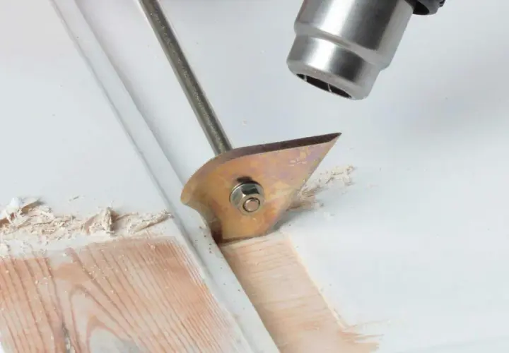Strumento per rimuovere pittura secca dal legno, con lama affilata che solleva schegge di vernice.