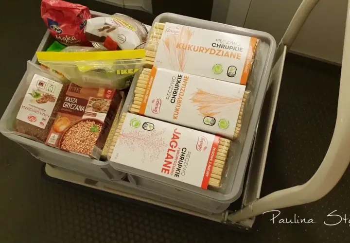 Koszyk z produktami długoterminowymi: kasza gryczana, chrupki kukurydziane i jaglane.