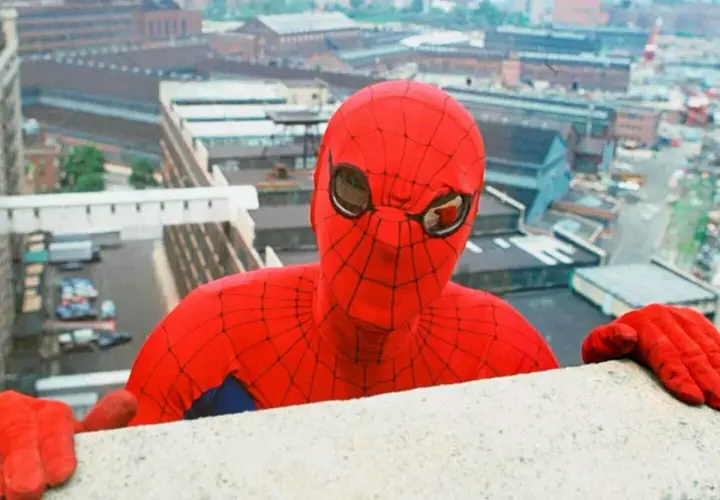 Le premier Spiderman acteur, Nicholas Hammond, se penche au-dessus d'un mur, regardant la ville.