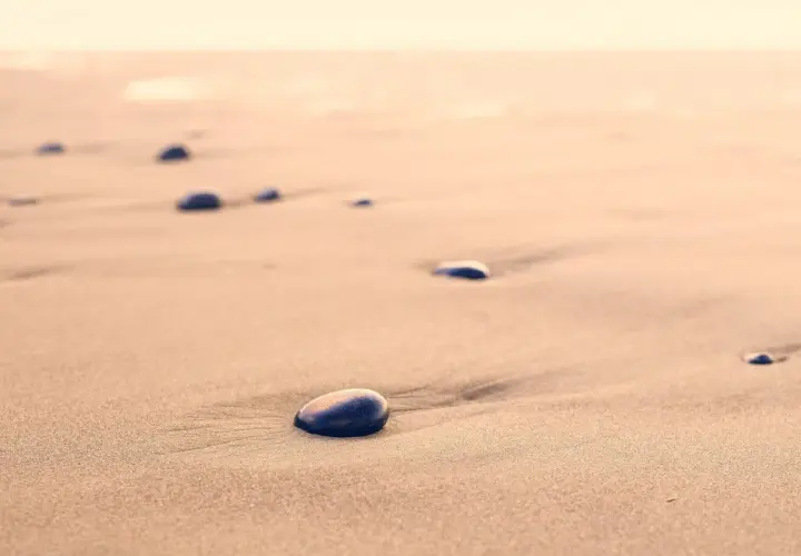 Kamienie na piaszczystej, dzikiej plaży, jak przebój Stana Borysa, tworzą ślady na piasku.