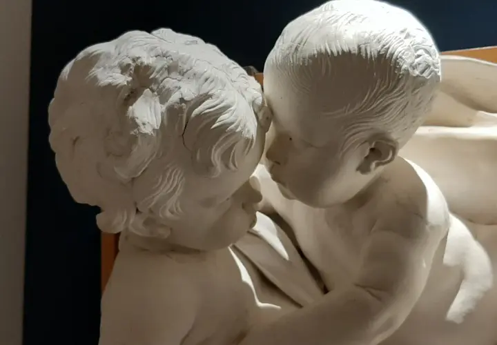 Due putti in stucco, un'opera di Giacomo Serpotta, si abbracciano teneramente.
