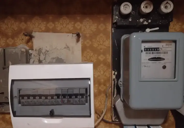 Zabezpieczenie przedlicznikowe obok licznika energii elektrycznej i białej skrzynki z bezpiecznikami.
