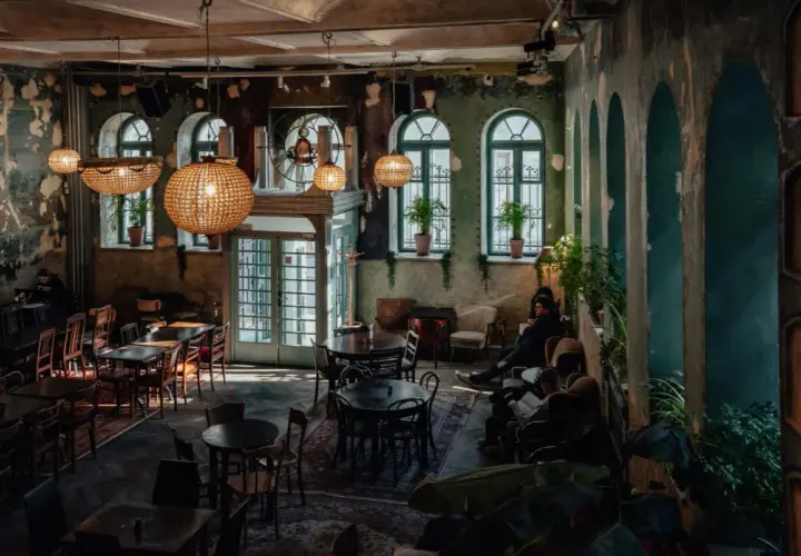 Wnętrze pełne uroku, z dużymi, okrągłymi lampami i zielonymi akcentami. Idealne miejsce na relaks w jednej z klimatycznych restauracji w Krakowie.