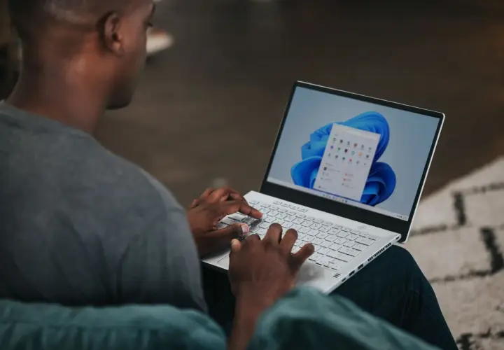 Mężczyzna na laptopie z systemem Windows 11, szukający informacji, jak zmienić nazwę użytkownika Windows 11.