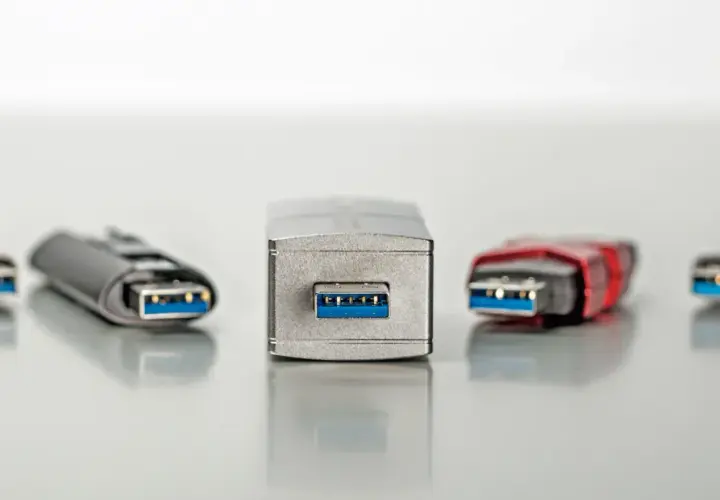 Fünf USB-Sticks in verschiedenen Designs, alle mit blauem Anschluss. Einer davon, der mittlere, wirkt besonders robust, fast wie ein Relikt aus der Zeit der USB 1.0 Geschwindigkeit.