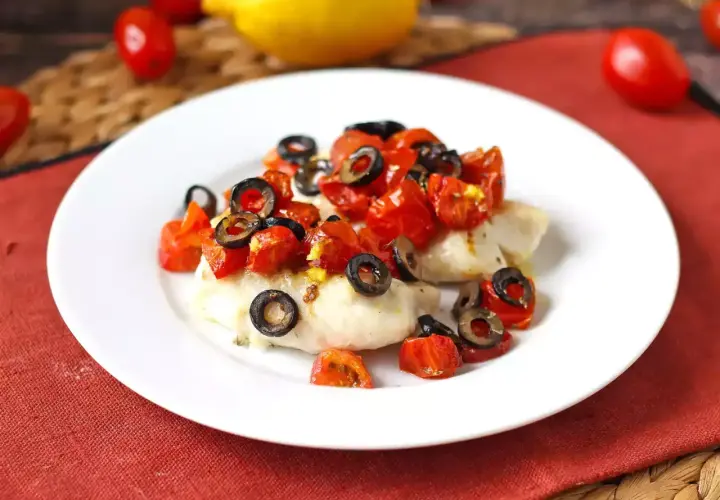Delizioso merluzzo in friggitrice ad aria, condito con pomodorini e olive nere, pronto per essere gustato.