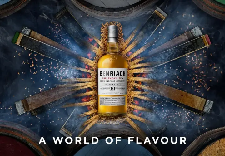 Bouteille de whisky BenRiach The Smoky Ten, entourée de fûts et d'épis de blé, évoquant le savoir-faire de la distillerie.