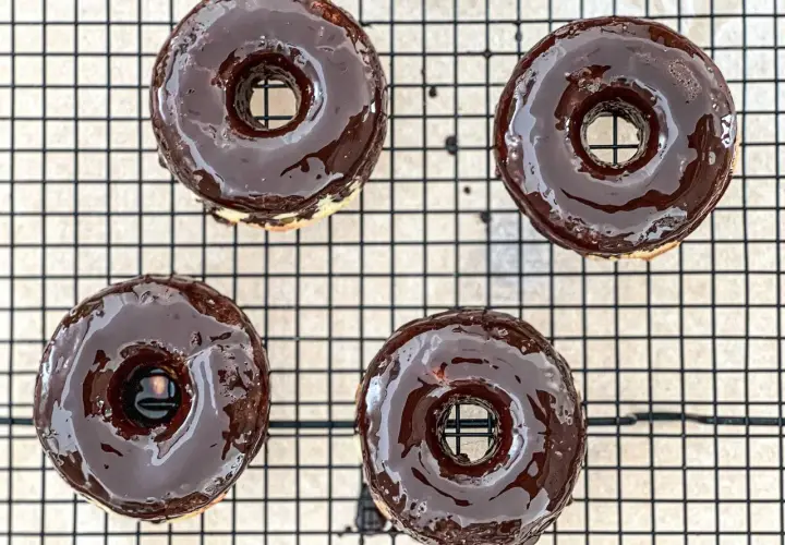 Cuatro deliciosos donuts glaseados con chocolate oscuro, listos para disfrutar. ¡Así es como hacer donuts caseros!