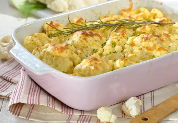 Cavolfiore al forno con pangrattato e formaggio fuso, guarnito con rosmarino fresco. Un piatto invitante e saporito.