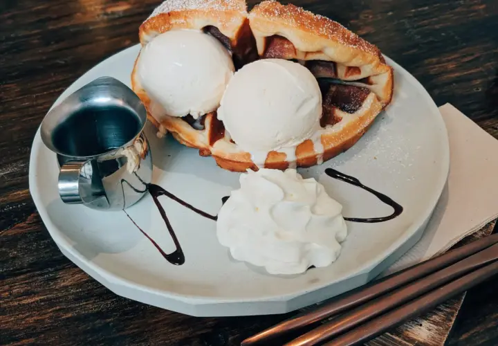 Pyszne bacio lody na ciepłym gofrze z bitą śmietaną i polewą czekoladową. Idealny deser na każdą okazję.