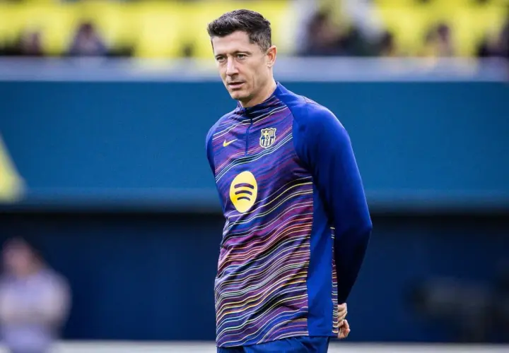 Robert Lewandowski w stroju FC Barcelona, w tle niebieska ściana. Wokół niego krążą barcelona pogłoski transferowe.