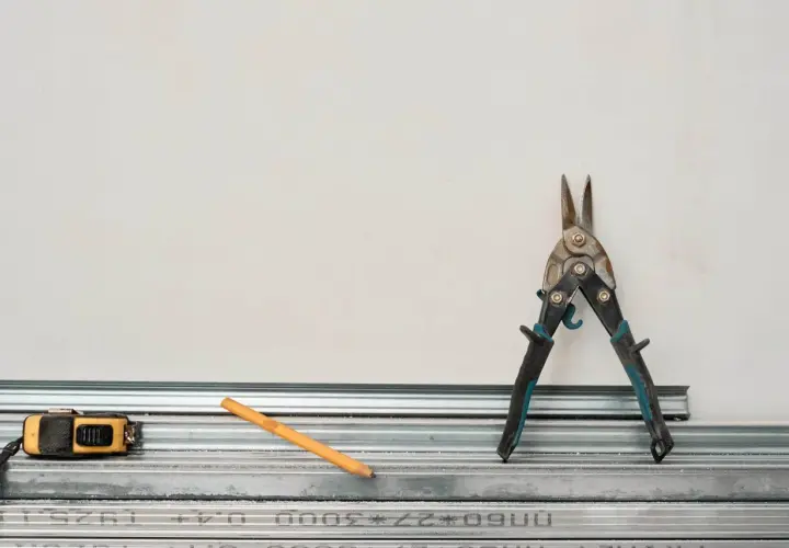 Outils pour comment couper un rail de placo : cisaille, mètre, crayon. Prêt à construire !