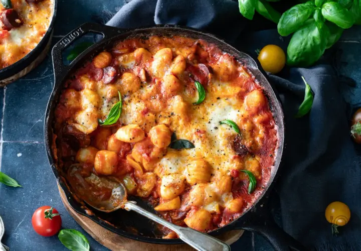 Gnocchi z pomidorami i mozzarellą zapieczone w żeliwnej patelni, ozdobione bazylią. Pyszne danie, które zachwyci każdego.