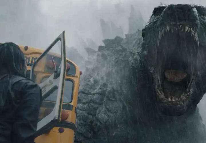 Enorm Godzilla vrålar mot en gul skolbuss i regnet, en del av **Monarch Legacy of Monsters**.